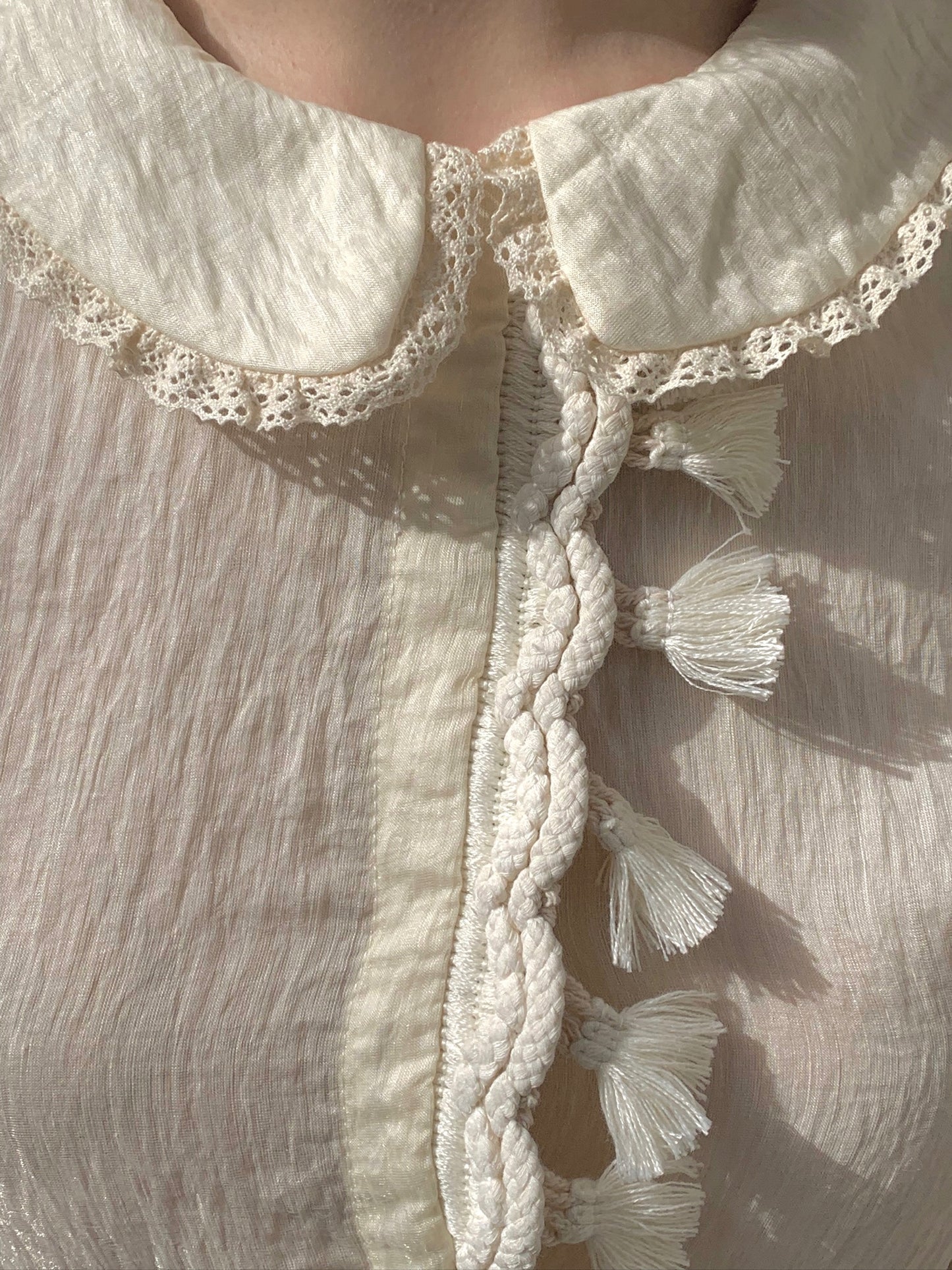 Beige doll shirt with a ruffled collar, lace tassels and an asymmetrical design