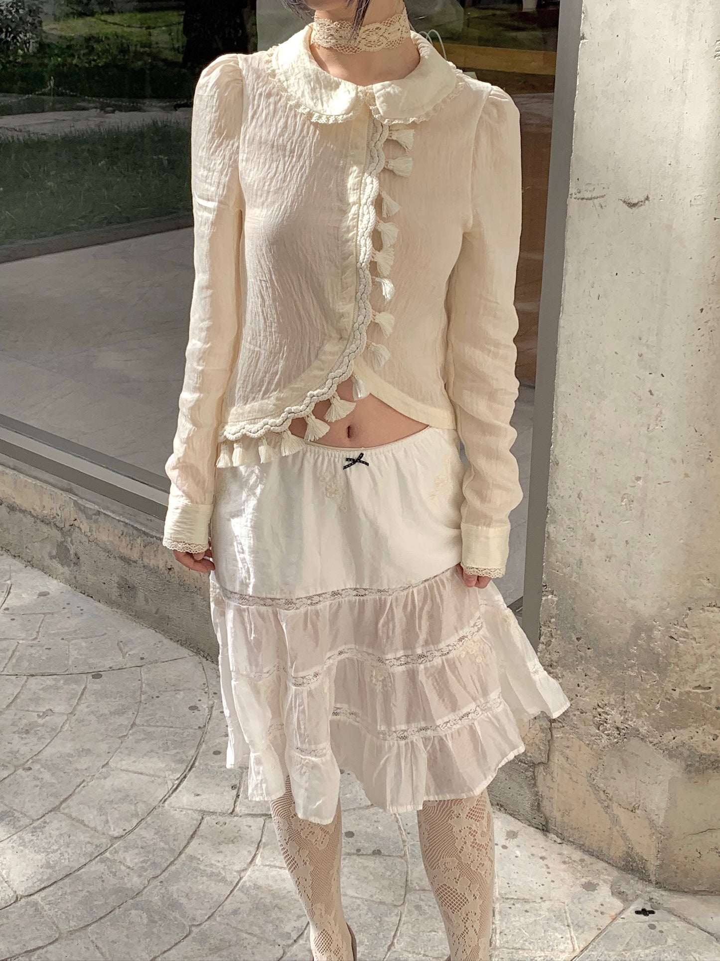 Beige doll shirt with a ruffled collar, lace tassels and an asymmetrical design