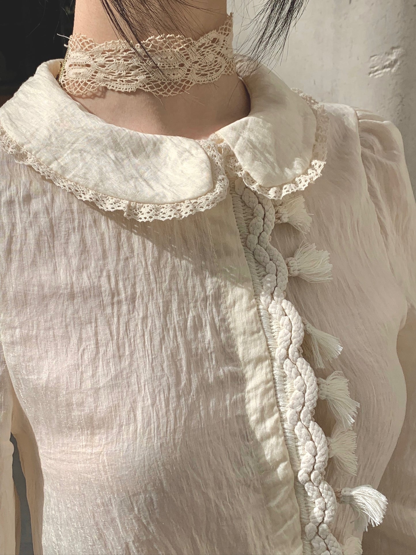 Beige doll shirt with a ruffled collar, lace tassels and an asymmetrical design