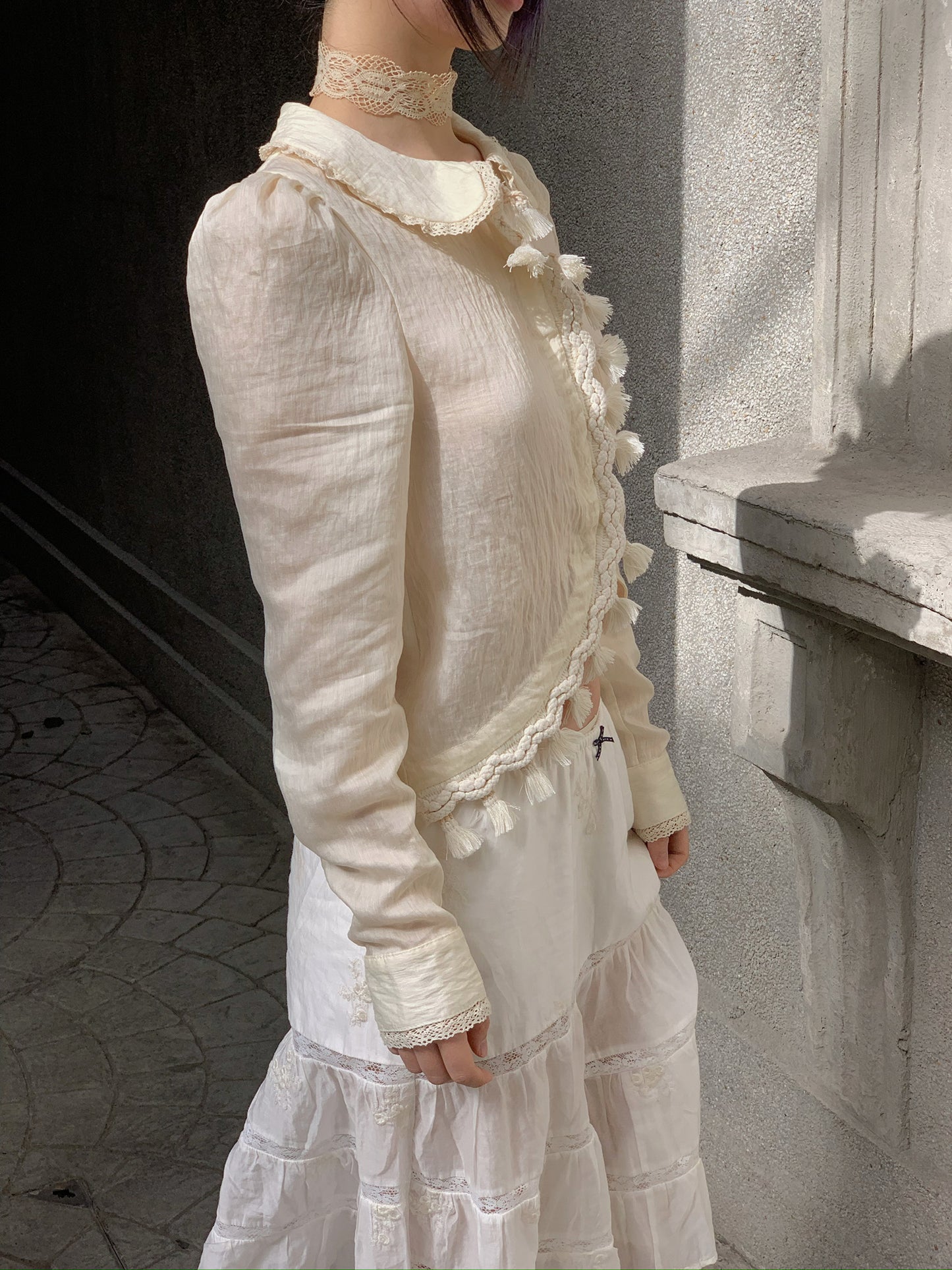 Beige doll shirt with a ruffled collar, lace tassels and an asymmetrical design